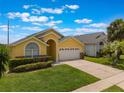Beautiful yellow single Gathering home with two car garage, arched entryway, and green lawn at 2685 Oneida Loop, Kissimmee, FL 34747