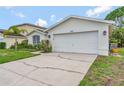 Home exterior showcasing a two-car garage, manicured lawn, and mature landscaping under a bright blue sky at 307 Balmoral Ct, Davenport, FL 33896