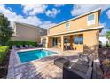 Backyard oasis with a sparkling pool, brick patio, covered seating area, and lush greenery for ultimate relaxation at 321 Lasso Dr, Kissimmee, FL 34747