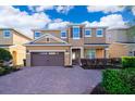 Charming two-story home with a two-car garage, brick driveway, and beautifully landscaped front yard under sunny skies at 321 Lasso Dr, Kissimmee, FL 34747