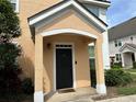 Exterior shot of peach siding, white trim, and a black front door with a welcome mat at 3301 Soho St # 104, Orlando, FL 32835