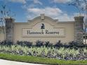 Elegant community sign with stone accents surrounded by neatly landscaped greenery against a partly cloudy sky at 3886 Whitney Way, Haines City, FL 33844