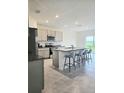Bright kitchen features grey cabinets, granite countertops, stainless appliances, and seating at the island overlooking the backyard at 3886 Whitney Way, Haines City, FL 33844