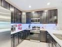 Modern kitchen featuring dark cabinets, stainless steel appliances, and light countertops at 4850 Coral Castle Dr, Kissimmee, FL 34746