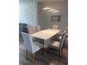 Elegant dining room with a glossy table, upholstered chairs, and accent wall at 8121 Fan Palm Way, Kissimmee, FL 34747