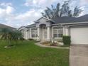 Well-maintained single-story home boasts a lush green lawn, landscaped garden beds, and a two-car garage at 852 Adour Dr, Kissimmee, FL 34759