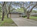 Single-story home with stone accents, two-car garage, and mature trees at 9905 Nicoma Ln, Orlando, FL 32817