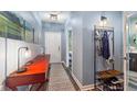 Hallway with wood floors, light blue walls, golf-themed artwork and black metal coatrack with shoe storage at 1064 Quaker Ridge Ln, Davenport, FL 33896