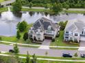 Beautiful home with lush landscaping, a paver driveway, and a serene lake view featuring a fountain at 10950 Belle Maisons Dr, Orlando, FL 32832