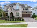 Inviting two-story home boasting a stone facade, arched entryway, and a paver driveway, complemented by manicured landscaping at 10950 Belle Maisons Dr, Orlando, FL 32832