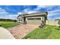 Well-kept home with stone accents, a brick driveway, and green lawn, offering a welcoming and classic design at 148 Whirlaway Dr, Davenport, FL 33837