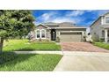 Attractive home featuring stone detailing, a two-car garage, and a brick driveway, set in a landscaped yard at 148 Whirlaway Dr, Davenport, FL 33837