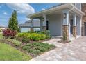Charming front yard with lush landscaping, a brick pathway, and a covered porch at 15600 Vetta Dr, Bella Collina, FL 34756