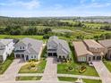 Aerial view of a beautiful gray home with a two-car garage, complemented by lush greenery at 16049 Volterra Pt, Bella Collina, FL 34756
