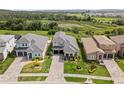 Aerial view of the home showcasing its lush landscaping and paver driveway in a neighborhood setting at 16049 Volterra Pt, Bella Collina, FL 34756