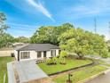 Landscaped single-story home with a manicured lawn, mature trees, and a newly paved driveway at 3804 Anthony Ln, Orlando, FL 32822