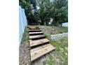Wooden steps lead up a small hill in the backyard towards a white privacy fence at 453 Alston Dr, Orlando, FL 32835