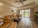 Cozy living room with wood floors, a ceiling fan, and sliding glass doors leading to an outdoor patio at 7650 Whisper Way # 102, Reunion, FL 34747