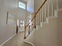 Bright foyer features a high ceiling, tiled floor, and a staircase with wooden handrails at 2735 Scarborough Dr, Kissimmee, FL 34744