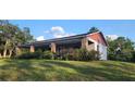 Inviting home featuring a spacious porch with brick columns and mature landscaping and a large, grassy yard at 600 Lake Butler Ave, Osteen, FL 32764
