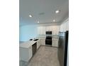 Well-lit kitchen featuring new stainless steel appliances and a gray tile floor at 7717 Stone Creek Trl, Kissimmee, FL 34747