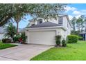 Two-story home with attached garage, well-manicured lawn, and mature landscaping at 909 Troon Cir, Davenport, FL 33897