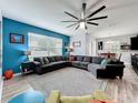 Open-concept living room with modern furniture, a blue accent wall and luxury vinyl flooring at 12606 Old Plantation Ln, Orlando, FL 32824