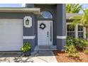 Close-up of a well-adorned front door with decorative wreath and accentuating potted plants at 138 Hidden Pointe Ln, Groveland, FL 34736