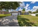 Single-story home featuring a well-manicured lawn and mature trees, enhanced by a clear blue sky at 138 Hidden Pointe Ln, Groveland, FL 34736