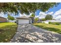 Landscaped front yard featuring an asphalt driveway leading to an attached two car garage at 138 Hidden Pointe Ln, Groveland, FL 34736