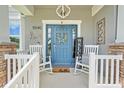 Welcoming porch with rocking chairs, charming decor, and attractive blue front door at 15540 Blackbead St, Winter Garden, FL 34787