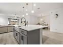 View of the kitchen island featuring modern pendant lighting, sink, faucet, and hardwood floors at 19267 Allium Pl, Orlando, FL 32827