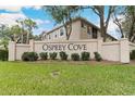 Osprey Cove entrance sign surrounded by manicured green lawn and mature trees at 2832 Osprey Cove Pl # 102, Kissimmee, FL 34746