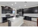 Modern kitchen featuring black cabinets, stainless steel appliances, a kitchen island, and tile floors at 3853 Cortland Dr, Davenport, FL 33837