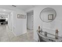 Bright hallway featuring tiled flooring, neutral walls, decorative table with round mirror leading to the living areas at 4338 Finch Ln, Kissimmee, FL 34746