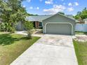 View of the front of the single-story home with a concrete driveway, lush grass and mature trees at 4607 Pine Lake Dr, St Cloud, FL 34769