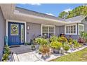 Inviting front porch with vibrant plants, stone accents, and a bright blue door at 6396 Bennett Ct, St Cloud, FL 34771