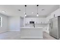 Contemporary kitchen with white cabinetry, stainless steel appliances, and a center island with pendant lights at 7 Spring Pass, Ocala, FL 34472