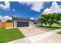 Charming single-story home featuring a gray-tone garage, solar panels, a sidewalk, and well-maintained landscaping at 12104 Shallot St, Orlando, FL 32837