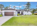 Charming single-story home with a well-manicured lawn, landscaped garden beds and a two-car garage at 2668 Coachman Dr, Deltona, FL 32738