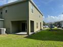 A view of the townhouse's grassy backyard, covered patio, and sliding glass door to the house at 2940 Tanzanite Ter, Kissimmee, FL 34758
