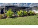 Screened-in patio with a well maintained lawn and lush tropical plantings at 301 Terranova Blvd, Winter Haven, FL 33884