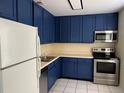Well-lit kitchen boasts white appliances, blue cabinetry, and stainless steel oven and microwave at 4085 Dijon Dr # 4085J, Orlando, FL 32808
