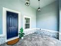 Inviting front porch with a blue front door, stone accents, neutral pavers and stylish hanging lights at 41 Orchid Ct, Kissimmee, FL 34759