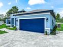 The side of this beautiful single-story home has an attached garage with a blue garage door and a lovely paver driveway at 41 Orchid Ct, Kissimmee, FL 34759