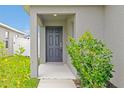 Inviting covered front door, featuring colorful plants, and gray exterior at 4505 Hummingbird Ln, Haines City, FL 33844