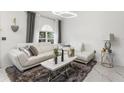 Bright living room featuring a stylish white sofa, marble floors, a modern coffee table, and elegant decor at 512 Yellow Tail Pl, Chuluota, FL 32766