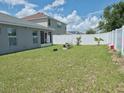 Spacious backyard showcasing a large grassy area, white vinyl fence, and a screened-in porch at 546 Lorient Dr, Eagle Lake, FL 33839