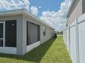 Exterior view of the side yard featuring green grass, home's wall, and a privacy fence at 546 Lorient Dr, Eagle Lake, FL 33839