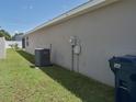 Side yard featuring lush green grass, home's exterior wall, and an air conditioning unit at 546 Lorient Dr, Eagle Lake, FL 33839